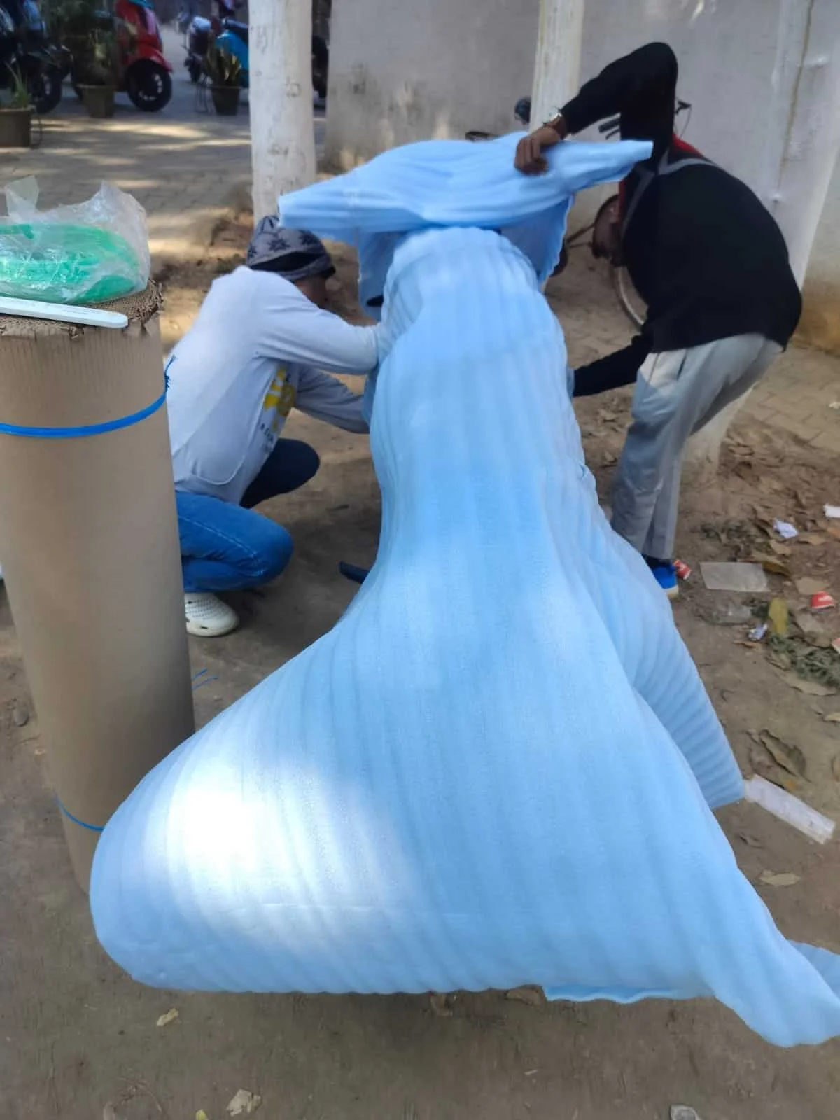 Workers loading large wrapped items for moving in Ranchi.